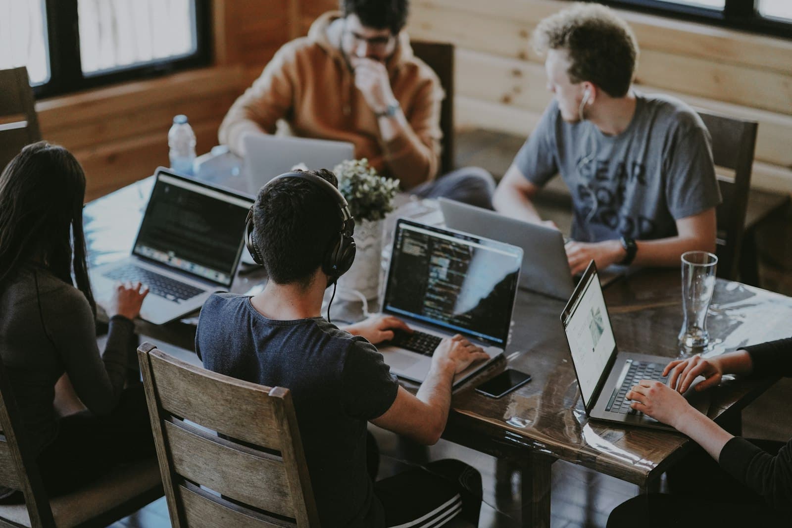 Software team collaborating at a shared table with laptops and code on screen